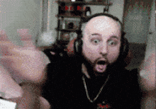 a bald man with a beard is wearing headphones and a chain around his neck .