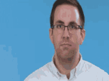 a man wearing glasses is blowing a kiss with his hand