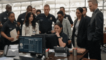a group of police officers are looking at a computer screen which has the letter e on it