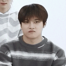 a young man wearing a striped sweater is making a face .
