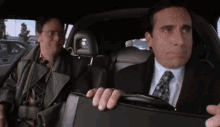 a man in a suit and tie is sitting in the back seat of a car with another man