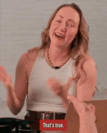 a woman in a white tank top is laughing with a red box that says that 's true