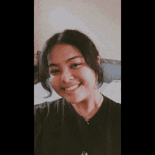 the girl is wearing a black shirt and a cross necklace and smiling .