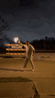 a man holding a firework in front of a construction keep sign