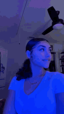 a woman is standing in a room with a ceiling fan and blue lights .