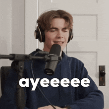 a young man wearing headphones is singing into a microphone and the word ayeeee is on the screen behind him