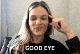 a woman is smiling and making a good eye gesture with her hand .