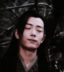 a close up of a man 's face with his eyes closed in a dark room