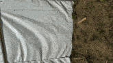 a white tarp is laying on the ground next to a wooden stick