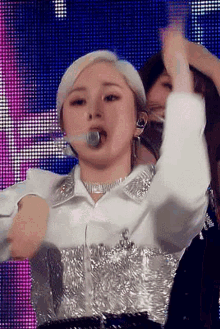 a woman in a white shirt is singing into a microphone while dancing on a stage .