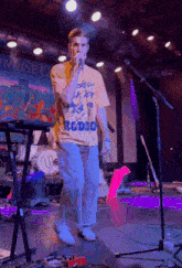 a man singing into a microphone wearing a yellow shirt that says studio on it