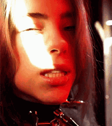 a close up of a woman 's face with a red light behind her