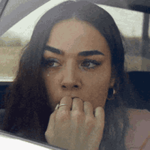 a woman with a ring on her finger is sitting in a car