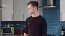 a man standing in a kitchen with a microwave and a toaster