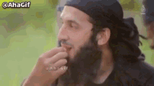 a man with a beard is eating a piece of food .