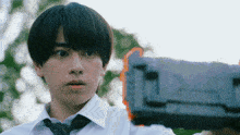 a young man in a white shirt and tie is holding a gun