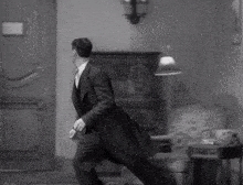 a black and white photo of a man in a suit running