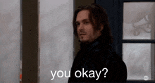 a man standing in front of a door with the words you okay written below him