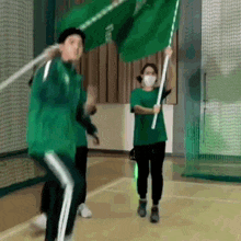 a group of people in green shirts are holding green flags .