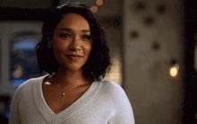 a close up of a woman wearing a white sweater and a necklace .