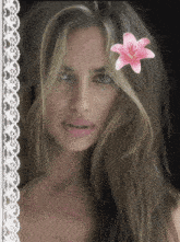 a woman with a pink flower in her hair looks at the camera