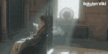 a man sits in a chair in front of a window with rakuten viki written in the corner