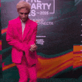 a man in a pink suit is dancing in front of a sign that says party es-2025
