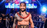 roman reigns is wearing a world heavyweight wrestling championship belt while standing in front of a crowd .