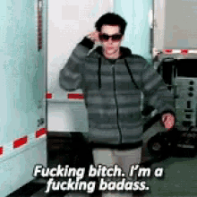 a man wearing sunglasses is standing in front of a trailer and saying fucking bitch i 'm a fucking badass