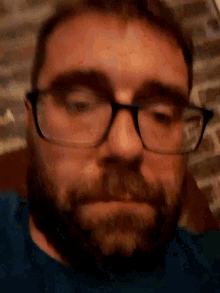 a man with glasses and a beard is laying down on a bed