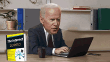 a man sitting at a desk with a book titled the internet for dummies
