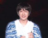 a young man wearing a blue and white striped sweater smiles