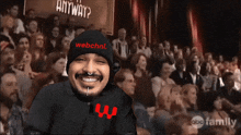 a man wearing a webchnl hat is smiling in front of a crowd of people