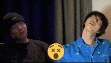 a man in a black hat and a man in a blue shirt are standing next to each other in a room .