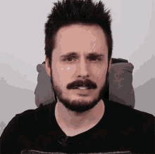 a man with a beard and mustache is wearing a black shirt that says ' nintendo ' on it