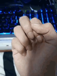 a close up of a person 's hand with a blue keyboard in the background
