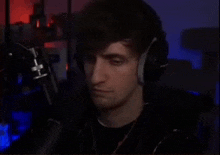 a man wearing headphones and a microphone is sitting in front of a microphone .