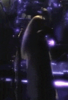 a woman stands in front of a microphone with her hands in the air