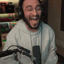 a man wearing headphones and glasses is laughing in front of a microphone with the letter r on it
