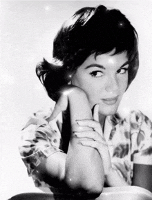 a black and white photo of a woman with her hands on her chin