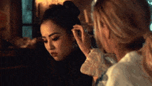 a woman is putting earrings on a woman 's ear .