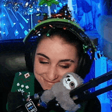 a woman wearing headphones and holding a stuffed sloth with a sign that says save lives