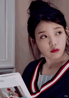 a woman with a bun on her head is reading a book called galaxy