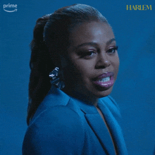 a woman is wearing a blue jacket and earrings and the word harlem is on the bottom right