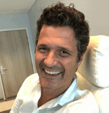 a man in a white shirt is smiling in a photo taken by a camera