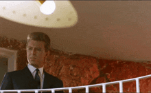 a man in a suit and tie standing on a balcony