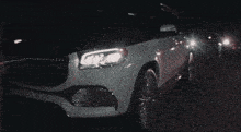 a man wearing a hat and sunglasses is standing next to a white car