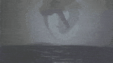 a giant squid is flying over the ocean in the fog .