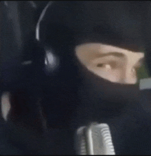 a person wearing a black mask and headphones is talking into a microphone .