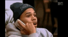 a man wearing a beanie is talking on a cellphone